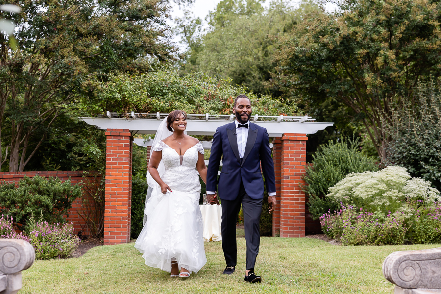 Couple walking hand in hand through the gardens.