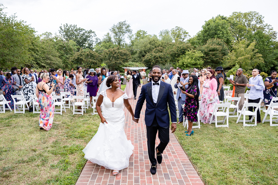 Couple walking hand in hand through the gardens.