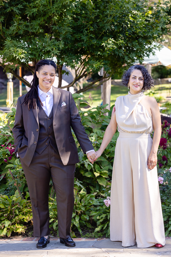 holding hands during their Zinnia garden wedding celebration